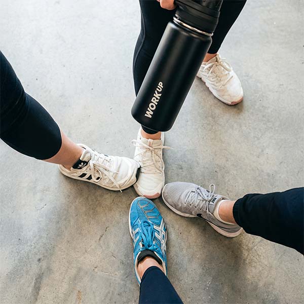 Fire personer i træningscenter samler fødderne i fællesskab.