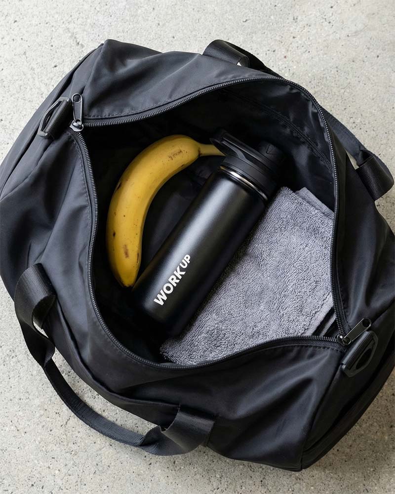 WORK UP-drikkeflaske i træningstaske ved siden af banan og håndklæde.